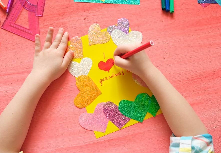 Little,girl,making,card,for,grandma.,colorful,pink,background,with