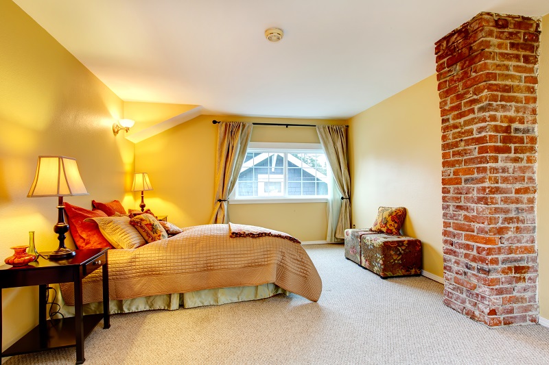 Bright,yellow,and,beige,bedroom,with,carpet,floor,,brick,colomn,